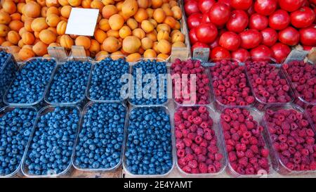 Heidelbeeren, Himbeeren und Brombeeren werden auf dem Markt verkauft. Es gibt Behälter mit Beeren auf der Theke. Stockfoto