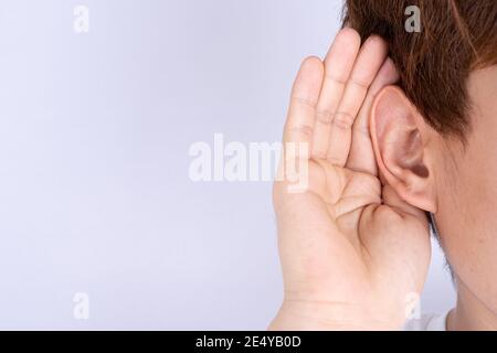 Mann Hörverlust oder schweres Gehör und Schröpfen seine Hand hinter seinem Ohr isolieren grauen Hintergrund, Gehörlose Konzept. Stockfoto