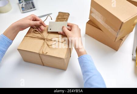 Hände, die Namensschild an Paketkasten bei der Post binden Stockfoto