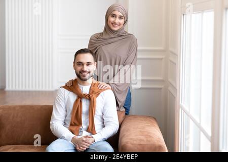 Fröhliche Junge Muslimische Familie Paar Posiert Zu Hause Stockfoto