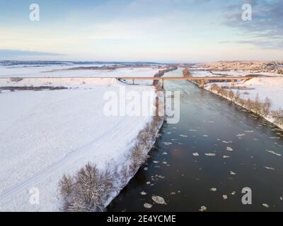 Brücke über den Dnepr River, verschneiten Wald an einem schönen Wintertag mit blauem Himmel und Wolken. Wunderschöne Winterlandschaft Stockfoto