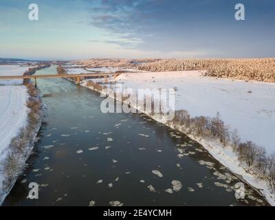 Brücke über den Dnepr River, verschneiten Wald an einem schönen Wintertag mit blauem Himmel und Wolken. Wunderschöne Winterlandschaft Stockfoto