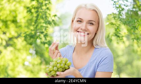 glückliche Frau essen Trauben Stockfoto