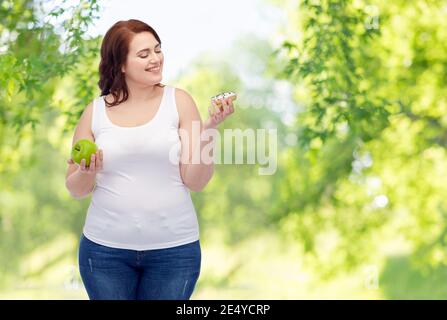 Plus Größe Frau Wahl zwischen Apfel und Donut Stockfoto