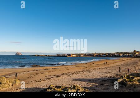 North Berwick, East Lothian, Schottland, Großbritannien, 25th. Januar 2021. UK Wetter: Sonnenschein entlang der Frith of Forth Küste an einem Tag mit einem klaren blauen Himmel und kaltem Wetter in West Bay mit dem Bass Rock am Horizont und ein paar Menschen zu Fuß am Strand Stockfoto