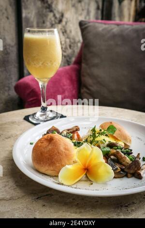 Eier benedikt mit Sauce Hollandaise, Pilz und frischem Saft. Breackfast-Konzept. Stockfoto