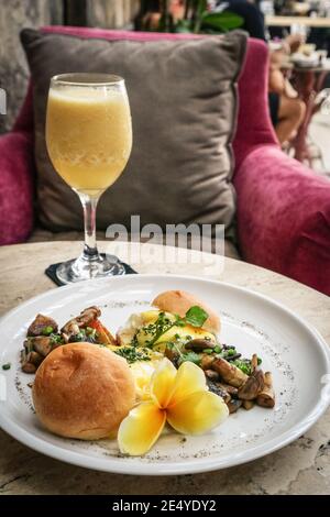 Eier benedikt mit Sauce Hollandaise, Pilz und frischem Saft. Breackfast-Konzept. Stockfoto