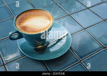 Kaffee mit Latte Art oben in blauer Tasse, Draufsicht Stockfoto