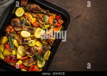 Gebackenes Huhn mit Gemüse, das im Ofen beim Backblech zubereitet wird. Stockfoto