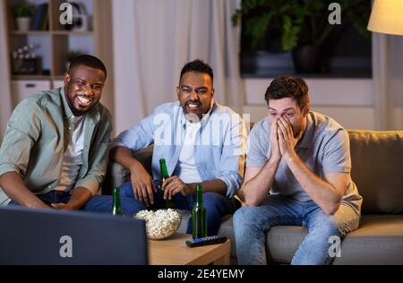 glücklich männlichen Freunde mit Bier vor dem Fernseher zu Hause Stockfoto