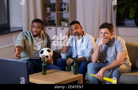Freunde mit Ball und Vuvuzela beim Fußballschauen Stockfoto