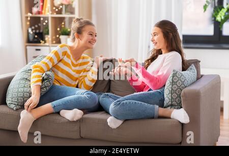 Glückliche Teenager-Mädchen reden auf dem Sofa zu Hause Stockfoto