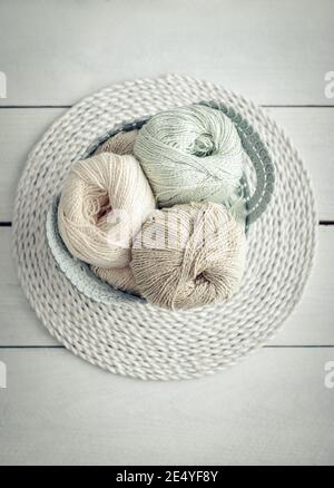 Farbige Garnkugeln und Stricknadeln im Korb auf hellem Hintergrund, Draufsicht Stockfoto
