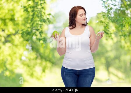 Plus Größe Frau Wahl zwischen Apfel und Donut Stockfoto