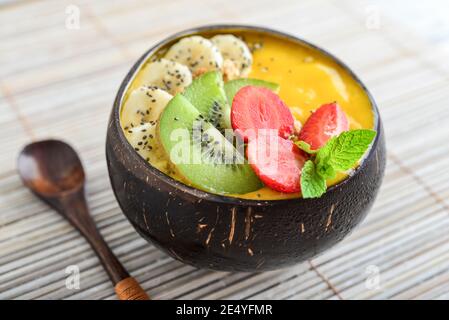 Mango Smoothie Schale mit Banane, Erdbeere, Kiwi, Granola und Chia Samen in Schale aus Kokosnussschale Stockfoto