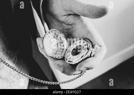 Überprüfen der Zeit in einem Anzug auf einem silbernen Gold Taschenuhr offen und in der Hand spät frühen tickende Uhr Vor dem Zeitplan in schwarz und weiß Stockfoto