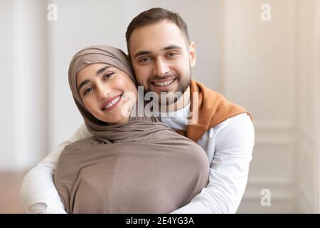 Fröhliche Junge Muslimische Paar Umarmt Posiert Im Haus Stehend Stockfoto