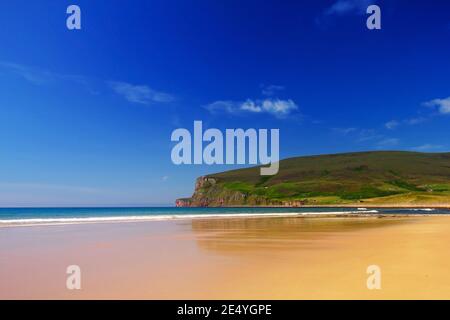 Orangefarbener Sandstrand mit grünen Hügeln und Klippen im Hintergrund, blauer Himmel mit weißen Wolken auf der schottischen Insel Hoy am Sommertag von Orkney Stockfoto