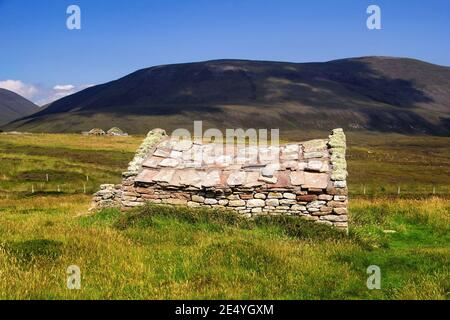 Traditionelles schottisches Bauernhaus aus Stein inmitten von grünem Gras Und dunkle Hügel im Hintergrund auf der schottischen Insel Hoy Am Sommertag von Orkney Stockfoto