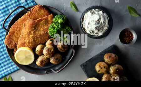 Schnitzel: Traditionelles österreichisches (deutsches) paniertes Fleisch mit Kartoffeln, Soße und Gewürzen Stockfoto