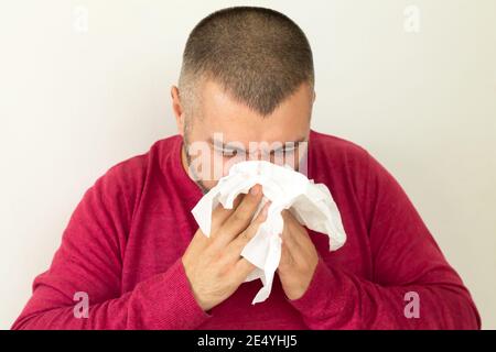 Junger Mann hält Taschentuch und niesen auf weißem Hintergrund Stockfoto