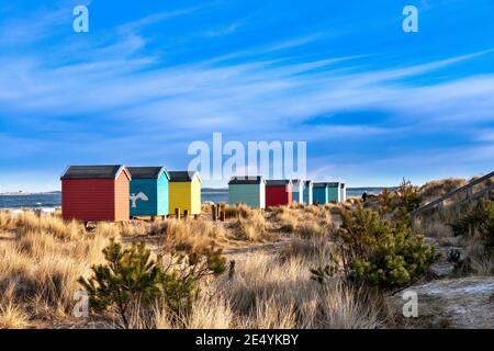 FINDHORN MORAY KÜSTE SCHOTTLAND DER STRAND MIT FARBIGEN CHALETS ODER HÜTTEN UND PERSONEN, DIE VORBEIGEHEN Stockfoto