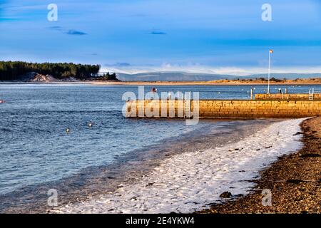 FINDHORN DORF MORAY KÜSTE SCHOTTLAND STEG UND EIS UND SCHNEE AM KIESSTRAND MIT BLICK AUF CULBIN WALD UND SCHWARZ INSEL Stockfoto