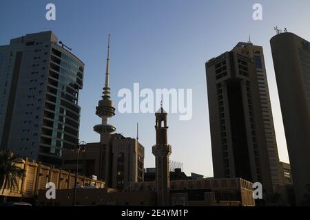 Kuwait-Stadt/Kuwait – 10. Januar 2021: Altes Moschee-Minarett mit Halbmondsymbol, das von modernen Wolkenkratzern in den Schatten gestellt wird Stockfoto