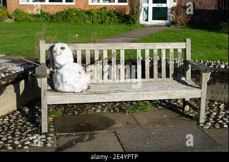 Eton, Windsor, Berkshire, Großbritannien. Januar 2021. Ein Schneemann schmilzt, als er auf einer Bank sitzt. Obwohl die Sonne heute den ganzen Tag scheint, sitzt immer noch eine Schneeschicht in schattigen Bereichen. Quelle: Maureen McLean/Alamy Live News Stockfoto