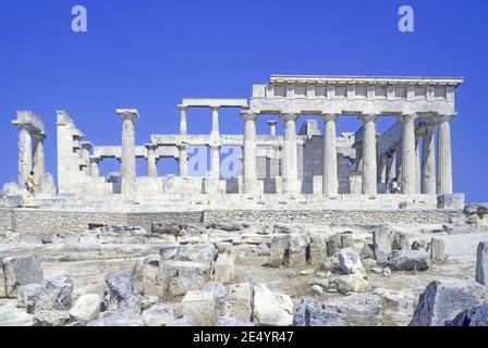 1986 Griechenland Tempel von Aphaia Aegina der Tempel von Aphaia oder Afea ist innerhalb eines Sanktuariums, das der Göttin Aphaia auf der griechischen Insel Aegina im Saronischen Golf gewidmet ist. Früher bekannt als der Tempel des Jupiter Panhellenius, ist der dorische Tempel jetzt als der Mutter-Göttin Aphaia gewidmet anerkannt, Touristen auf einer Führung genießen den Blick auf den griechischen Tempel, Ägina Griechenland EU Europa Stockfoto