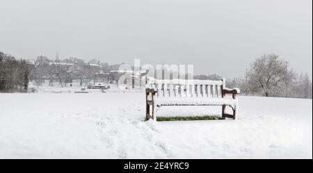 Felder von Harrow auf dem Hügel mit einer Bank unter dem Schnee und Harrow Schulgebäude im Hintergrund, England Stockfoto