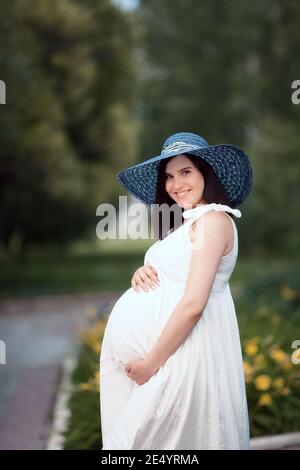 Junge schwangere Mädchen an einem Sommertag im Park. Mama wartet auf die Geburt des Babys Stockfoto