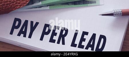 Notizblock mit Pay per Lead auf Holztisch und Euro-Scheinen darauf. SEO Internet Förderung Business-Konzept. Stockfoto