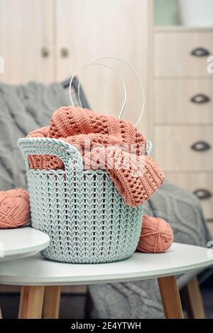 Korb mit Strickprojekt in Arbeit und Garn auf Kaffee Tisch in häuslichen Innenräumen Nahaufnahme Stockfoto