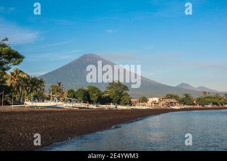Amed Strand in Bali, Indonesien. Traditionelle Fischerboote genannt Jukung auf dem schwarzen Sandstrand und Mount Agung Vulkan im Hintergrund. Stockfoto