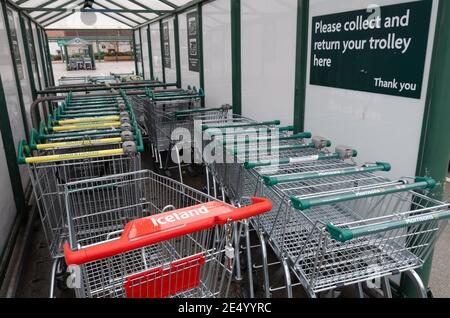 Rhyl; UK: Jan 01, 2021: Ein Trolley aus einem isländischen Supermarkt wurde in einem Trolley-Unterstand neben mehreren Morrisons Trolleys aufgestellt. Stockfoto