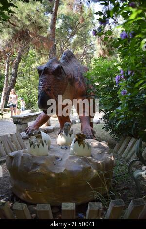 Dinosaurier-Statue im Waldpark in der Natur für Hintergrund. Realistisches Modell des Dinosauriers in der Nähe seines Nestes mit Eiern. Dinopark in der Türkei, Goynuk. Dinosaurier Stockfoto