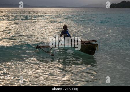 Junge Einheimische surft ein Outrigger-Kanu am Bougainville Strand, Papua-Neuguinea Stockfoto