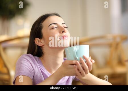 Glückliche Frau riecht Kaffee atmen frische Luft zu Hause Stockfoto