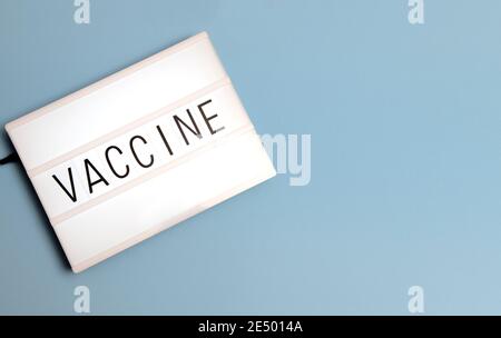 „Impfstoff“-Meldung auf einem Leuchtkasten mit blauem Hintergrund und Kopierbereich. Stockfoto