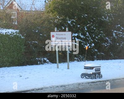 Schnee auf den Gehwegen hält den 6-rädrigen Raumschiff-Roboter nicht davon ab, Lebensmittel an die Bewohner in Wootton, Northampton, zu liefern; Januar 2021 Stockfoto