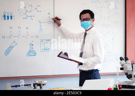 Naturlehrerin trägt Maske und unterrichtet im Klassenzimmer Stockfoto