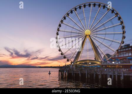 Das Seattle Great Wheel steigt 175 Meter über Pier 57, mit Blick auf die Skyline von Seattle und Elliott Bay, wenn die Sonne im Westen untergeht Stockfoto