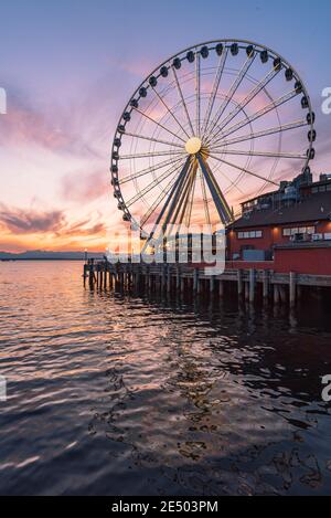 Das Seattle Great Wheel steigt 175 Meter über Pier 57, mit Blick auf die Skyline von Seattle und Elliott Bay, wenn die Sonne im Westen untergeht Stockfoto