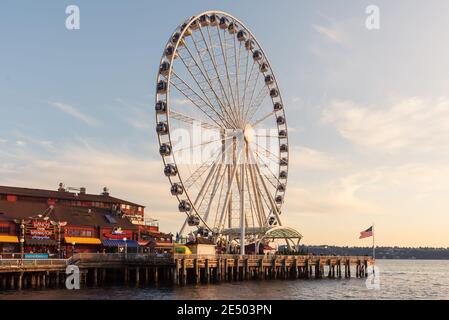 Das Seattle Great Wheel steigt 175 Meter über Pier 57, mit Blick auf die Skyline von Seattle und Elliott Bay, wenn die Sonne im Westen untergeht Stockfoto