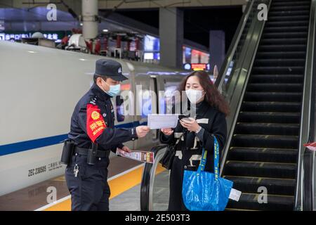 Chongqing, China. Januar 2021. Ein Polizeibeamter verteilt Informationsmaterialien zur epidemischen Prävention an einen Passagier am Bahnhof Chongqingbei in Chongqing, Südwestchina, 25. Januar 2021. Die Präventions- und Kontrollbemühungen gegen die COVID-19-Epidemie werden an Bahnhöfen in Chongqing verstärkt, um die Sicherheit der Passagiere zu schützen. Quelle: Huang Wei/Xinhua/Alamy Live News Stockfoto