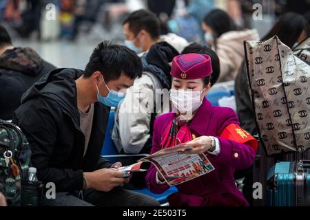 Chongqing, China. Januar 2021. Ein Mitarbeiter verteilt Flugblätter zur Verhütung von Epidemien an einen Passagier am Bahnhof Chongqingbei in Chongqing, Südwestchina, 25. Januar 2021. Die Präventions- und Kontrollbemühungen gegen die COVID-19-Epidemie werden an Bahnhöfen in Chongqing verstärkt, um die Sicherheit der Passagiere zu schützen. Quelle: Huang Wei/Xinhua/Alamy Live News Stockfoto