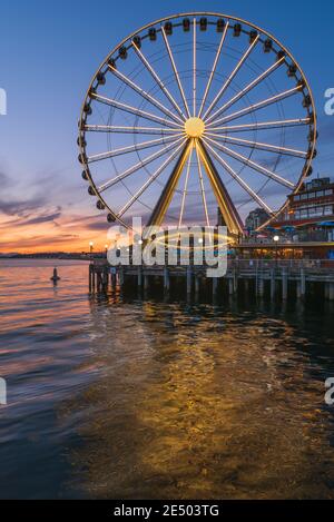 Das Seattle Great Wheel steigt 175 Meter über Pier 57, mit Blick auf die Skyline von Seattle und Elliott Bay, wenn die Sonne im Westen untergeht Stockfoto