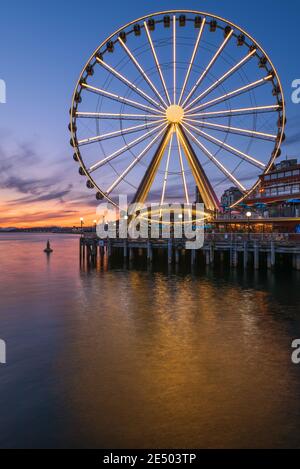 Das Seattle Great Wheel steigt 175 Meter über Pier 57, mit Blick auf die Skyline von Seattle und Elliott Bay, wenn die Sonne im Westen untergeht Stockfoto
