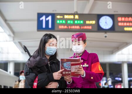 Chongqing, China. Januar 2021. Ein Mitarbeiter verteilt Flugblätter zur Verhütung von Epidemien an einen Passagier am Bahnhof Chongqingbei in Chongqing, Südwestchina, 25. Januar 2021. Die Präventions- und Kontrollbemühungen gegen die COVID-19-Epidemie werden an Bahnhöfen in Chongqing verstärkt, um die Sicherheit der Passagiere zu schützen. Quelle: Huang Wei/Xinhua/Alamy Live News Stockfoto